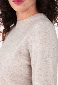 Light gray, knitted sweater with a ribbed crew neckline, featuring a soft texture and seamless shoulders, showcasing a slightly fitted silhouette.
