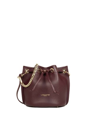 Petit sac seau en cuir rouge foncé avec bandoulière chaîne dorée et fermeture à cordon, affichant le nom de la marque "Lancaster Paris" en lettres dorées.