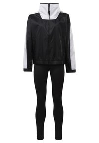 Veste zippée noir et blanc avec col montant associée à des leggings noirs moulants.