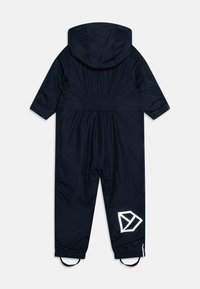 Tamnoplav snowsuit s kapuco z elastiko v pasu, reflektivni detajli logotipa in elastičnimi manšetami. Gladek, vodoodporen material z mat zaključkom.