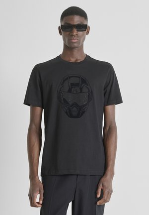 Camiseta negra con un gráfico texturizado de un diseño similar a un casco. Mangas cortas, cuello redondo, hecha de material de algodón suave.