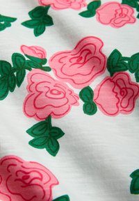 Rosa rosor och gröna blad tryckta på ett vitt strukturerat tyg, som visar ett blommönster med mjuka, böjda former och livliga färger.