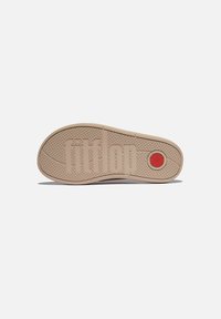 Lichtbeige rubberen schoenenzool met een gestructureerde grip, met een opvallend "fitflop" logo en een rode cirkelvormige accent op de hak.