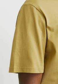 Short-sleeve, crew neck t-shirt in olive green cotton with smooth texture. Features a simple design and a straight hem.