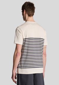 Crème T-shirt met korte mouwen, voorzien van een horizontaal marineblauw en wit streeppatroon. Zacht katoenen materiaal, ronde halslijn en een relaxte pasvorm.