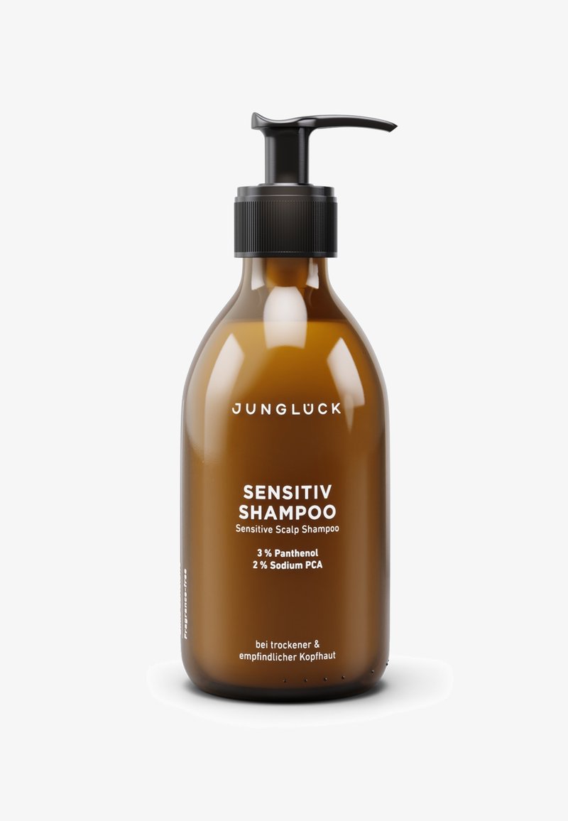 Brown plastic bottle with a black pump lid. White text on the front reads "SENSITIV SHAMPOO" and details ingredients and usage instructions.