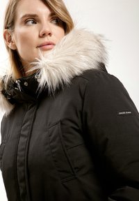 Czarna parka z odpinanym kapturem wykończonym sztucznym futrem, zapinana na zamek i zatrzaski, z bocznymi kieszeniami oraz naszywką z logo na rękawie.