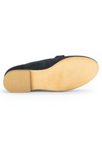 Schwarze Wildledersohle mit einem strukturierten Gummidesign, versehen mit einer beigen Seite, eingeprägtem Markenname und runder Form.