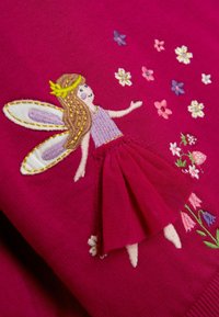Fuksia sviiter, millel on tikitud haldjas kuldsete aktsentidega, ümbritsetud värvikate lillemotiividega. Pehme kangas ning kihiline seeliku detail.