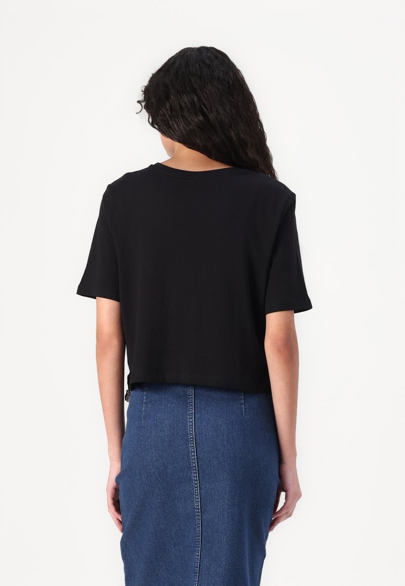 Czarny krótki T-shirt wykonany z miękkiego materiału z krótkimi rękawami, sparowany z niebieską spódnicą denimową z centralnym szwem i dopasowanym krojem.