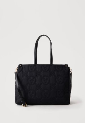 Sac cabas noir matelassé avec motifs circulaires et floraux en relief, deux poignées et une bandoulière réglable avec boucle dorée.