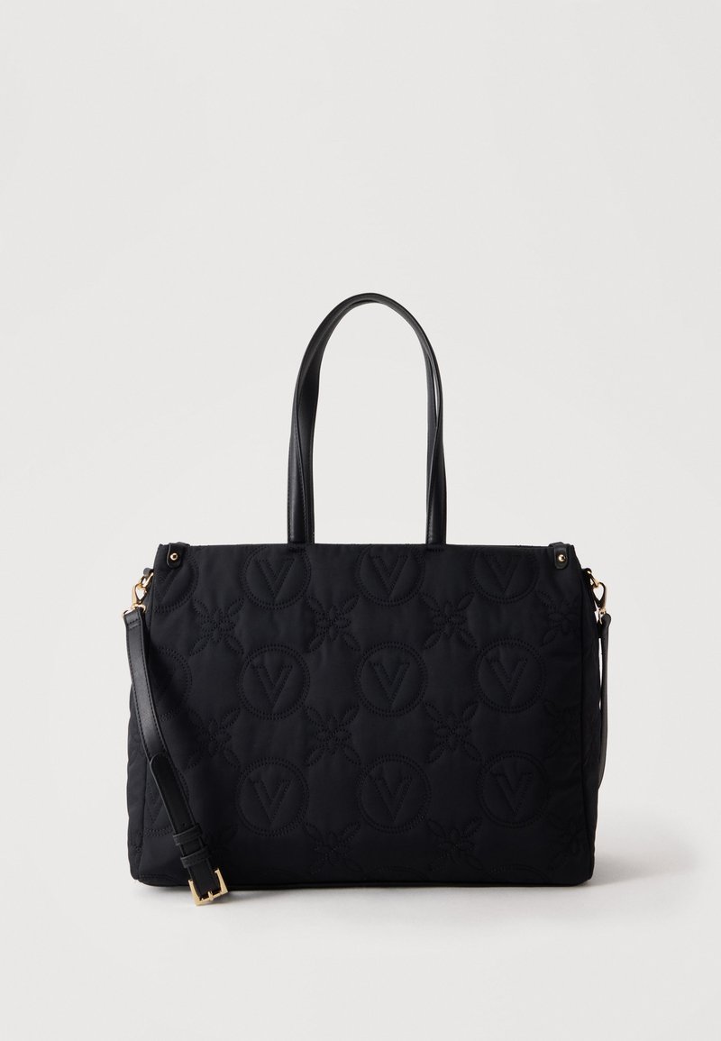 Sac cabas noir matelassé avec motifs circulaires et floraux en relief, deux poignées et une bandoulière réglable avec boucle dorée.