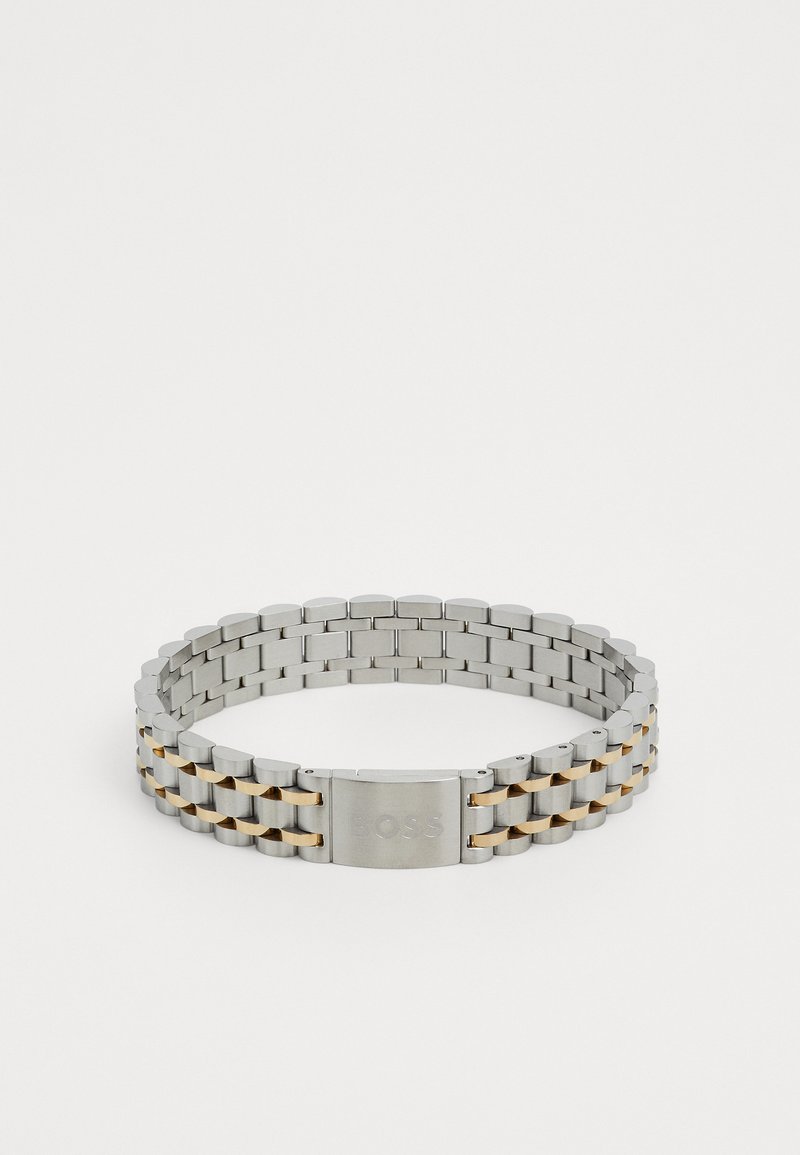 Bracelet en métal aux teintes argentées et dorées, composée de maillons entrelacés avec une texture lisse et un fermoir marqué "BOSS."