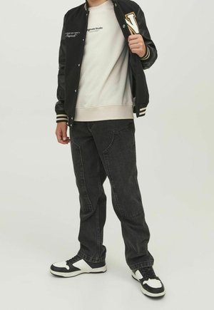 Black varsity jacket with white stripes, gray sweatshirt, dark gray jeans, and black-and-white sneakers. Casual outfit with sporty details.