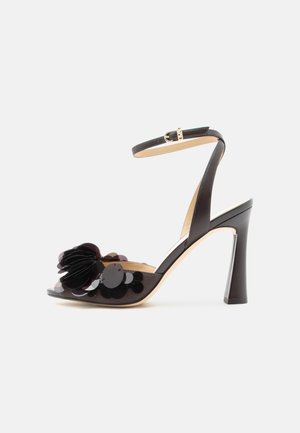 Sandalo nero con tacco alto, cinturino alla caviglia e grandi paillettes decorative nere e petali sulla fascia delle dita.