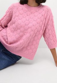 Hellrosa übergroßer Pullover mit Blattmuster, Rundhalsausschnitt und halblangen Ärmeln, aus weichem, gestricktem Stoff.