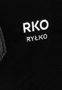 Czarny materiał teksturowany z błyszczącym srebnym logo zawierającym "RKO" oraz "RYŁKO" w kontrastujących rozmiarach czcionki, umieszczonym w wyraźny sposób.