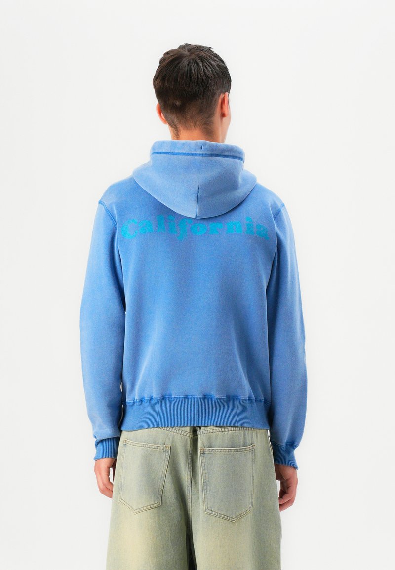 Sudadera azul con capucha de tela texturizada. "California" impreso en grandes letras verdes en la parte posterior. Cuerda ajustable en la capucha.