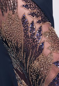 Netzstoff mit goldenen und blauen Pailletten, die in filigranen Blumen- und Blattmustern auf einem dunklen Kleidungsstück angeordnet sind.