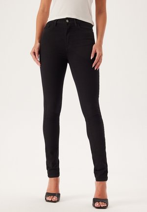Zwarte skinny jeans van rekbare denim. Heeft een klassieke vijf-pocketontwerp en sluiting met een knoop aan de voorkant. Gladde textuur, enkel-lange pasvorm.