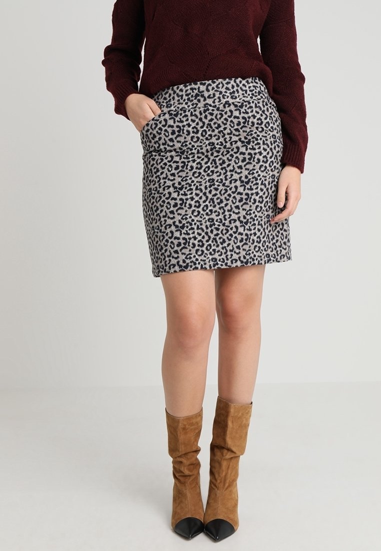 Falda de estampado de leopardo en tejido gris y negro, con un diseño ajustado y bolsillos laterales. Combinada con botas altas de ante marrones.