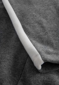 Dark gray fleece fabric with a contrasting white trim; soft texture and smooth finish. The design features a rounded edge, highlighting the layers.
