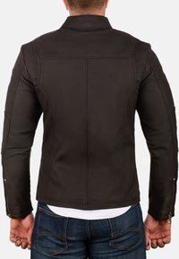 Zwarte leren jas met een slim-fit ontwerp, voorzien van een kleine kraag en zichtbare stiksels. Met ritssluitingen aan de mouwen en een gladde textuur.