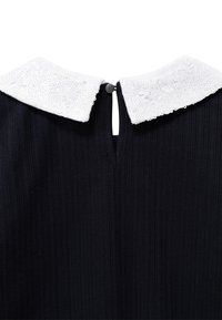 Czarna sukienka z prążkowanej tkaniny z białą, cekinową kołnierzykiem typu Peter Pan oraz małym zapięciem na guziczek z tyłu.