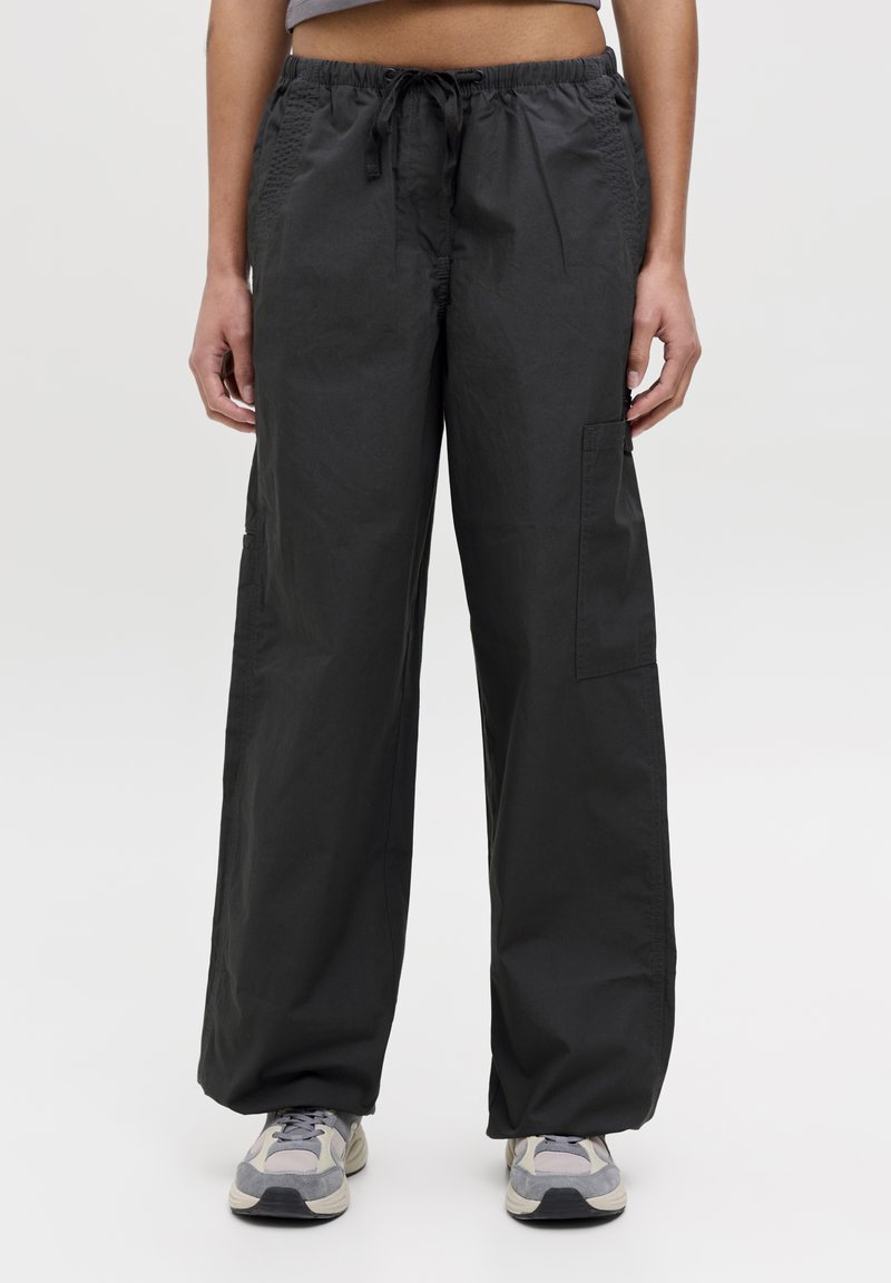 Pantaloni a gamba larga di colore grigio scuro realizzati in un tessuto leggero, con vita elastica e cordino. Presentano tasche laterali e tasche cargo.