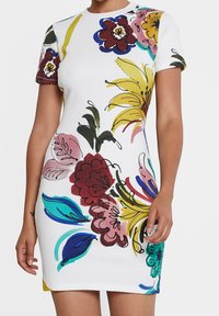 Robe à manches courtes côtelée blanche avec motifs floraux colorés. Présente des fleurs jaunes, roses et bleues audacieuses. Coupe cintrée, longueur au-dessus du genou.