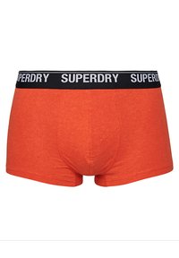 Boxers rojos de algodón con una cinturilla negra donde se repite el logo "SUPERDRY" en blanco. Diseño ajustado con una textura suave.
