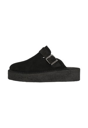 Sabots en suede noir avec une épaisse semelle plateforme, dotés d'une boucle latérale et d'un bout arrondi. Texture douce et design sobre.