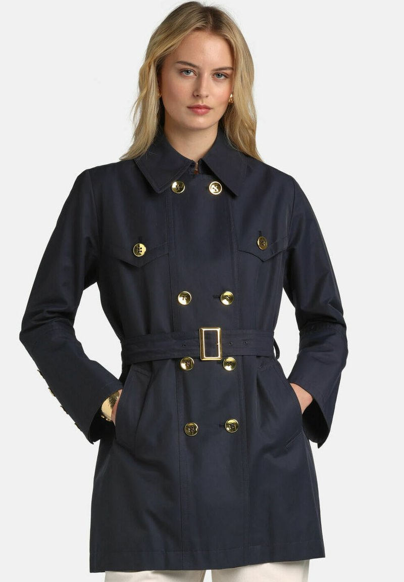 Palton trench albastru marin cu nasturi aurii, talie cu curea, design cu două rânduri de nasturi și buzunare laterale; textura fină a țesăturii.