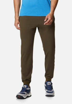 Olivgrüne Sporthosen mit schmaler Passform, elastischem Bund und seitlichen Taschen, kombiniert mit grauen und marineblauen Schuhen.