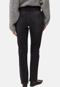 Svarta denimjeans med rak benpassform, hög midja och bakfickor. Inkluderat med en ljusgrå stickad tröja och platta skor.