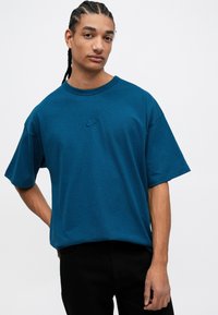 Kreklu ar apaļu kakla izgriezumu, izgatavots no mīkstas, teksturētas auduma, ar īsām piedurknēm. Tam ir mazs izšūts Nike logo uz krūtīm.