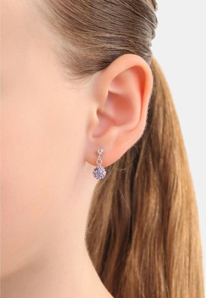 Silberne Ohrringe mit einem kleinen Ball-Design, das lila und klare Kristalle enthält, hängen an einem einfachen Haken und sind an einem menschlichen Ohr zu sehen.