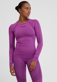 Sportieve lange mouwen top in levendig paars met textuurpanelen, een getailleerd ontwerp en logo op de borst. Gemaakt van flexibele, ademende stof.