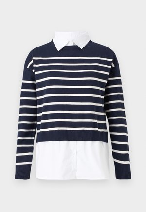 Maglione blu navy con strisce orizzontali bianche, scollatura rotonda, design cropped e una camicia bianca con colletto sotto. Tessuto a maglia testurizzato.