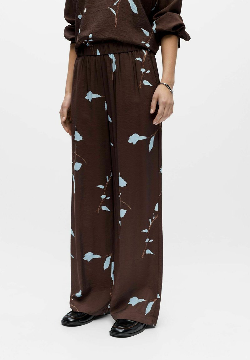 Pantalon marron à jambes larges avec un motif floral bleu, confectionné dans un tissu léger et texturé, doté d'une taille élastique pour le confort.