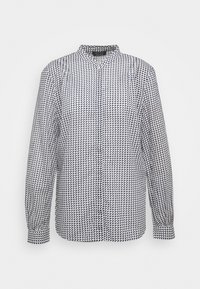 Camisa de patrón en blanco y negro con cuello mandarín, mangas largas y cierre de botones, que presenta un diseño geométrico en toda su superficie.