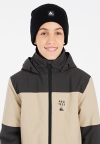 Schwarze Beanie und eine farbige Jacke in Beige und Dunkelgrau, mit einem Reißverschluss auf der Vorderseite und einem Logo auf der Brust. Glatte Textur.