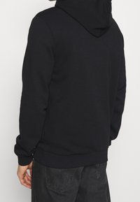 Schwarzer Kapuzenpullover mit lockerer Passform, gerippten Bündchen und Saum, einer glatten Textur und ohne sichtbare Muster oder Verzierungen.