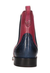 Botín de cuero en rojo y azul. Presenta detalles de brogue, paneles laterales elásticos y un sleek tacón negro. Acabado texturizado.