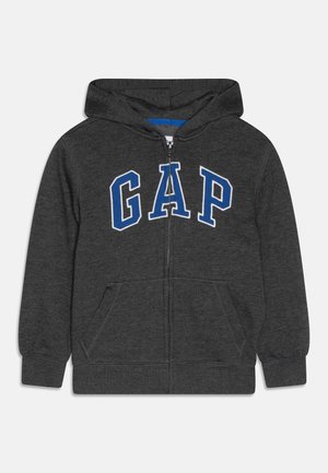 Sweat à capuche zippé gris foncé avec capuche attachée, poches kangourou, et logo "GAP" bordé de bleu sur la poitrine.