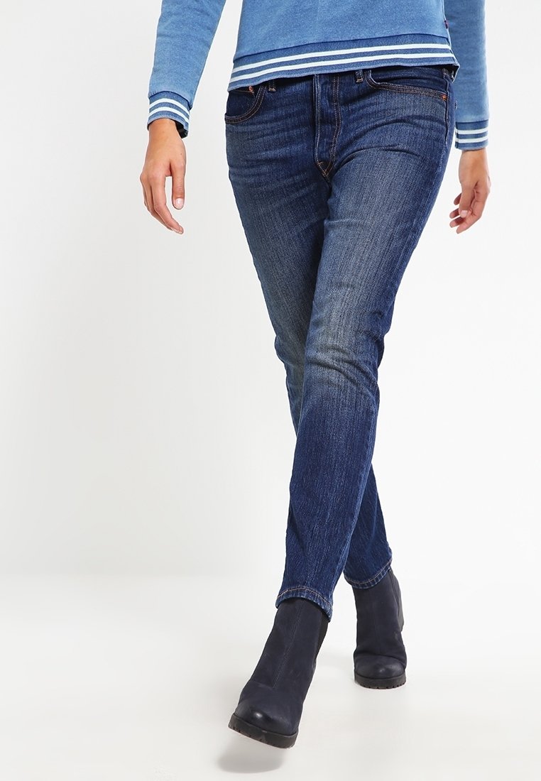 Tummansiniset farkut suoran leikkauksen ja pienen haalistuman kanssa. Yhdistetty vaaleansiniseen pitkähiharaiseen paitaan, jossa on valkoiset raidat hihansuissa.