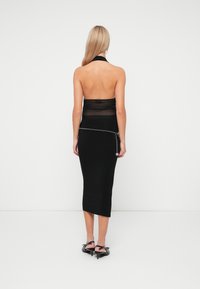 Black halter-neck dress with sheer material at the top and a smooth fitted skirt. Features a silver chain detail at the waist.