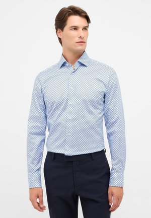 Camicia a maniche lunghe blu chiaro con un motivo geometrico in blu scuro. Collo classico, chiusura con bottoni davanti e design aderente.