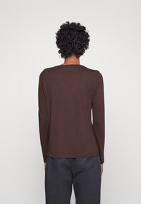 Braunes Langarmshirt mit Rundhalsausschnitt und glatter Textur, mit leicht abgerundetem Saum und taillierten Ärmeln.