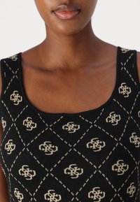 Black knit tank top featuring a diamond pattern with beige motifs. The neckline is rounded, and the fabric has a smooth texture.